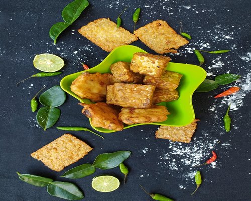 A well-portioned plate of traditional Indonesian food including rice, tempeh, and vegetables