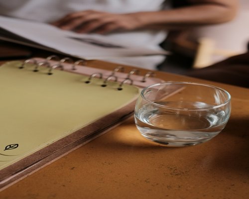 A glass of water next to an open notebook on a modern desk